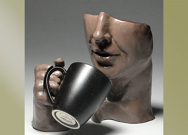 Sculpture of a face drinking coffee